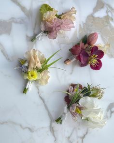 three different colored flowers sitting on top of a white marble countertop next to each other