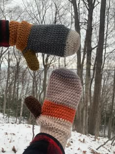 three crocheted mittens hanging from a tree in the snow