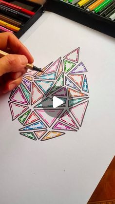 someone is drawing something with colored pencils on paper and it looks like an origami