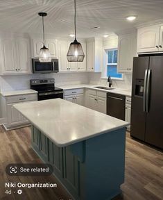 a kitchen with white cabinets and an island in front of a refrigerator freezer next to a stove top oven