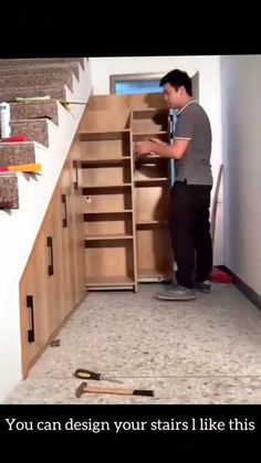 a man standing in front of a wooden cabinet next to a stair case with tools on it