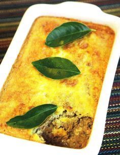 a casserole dish with spinach leaves on top and meat in the bottom