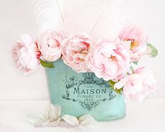 pink flowers are in a blue vase with feathers on the top and below it is a label that reads maison floret