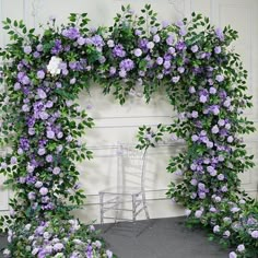 a chair sitting under a purple flower covered arch