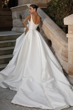 a woman in a white wedding dress standing on steps with her back to the camera