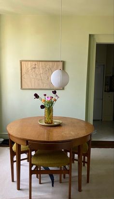 a dining room table with flowers in a vase on it and two chairs at the end