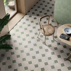 a chair and table in a room with green tiles on the floor, next to a potted plant