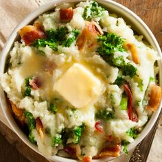 a bowl filled with mashed potatoes and broccoli topped with butter on top