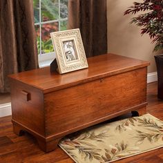 a wooden chest sitting on top of a hard wood floor next to a potted plant