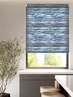 a kitchen with a window covered in roman shades and stools next to the counter