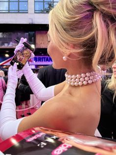 a woman in white gloves taking a picture with her cell phone at a convention or event