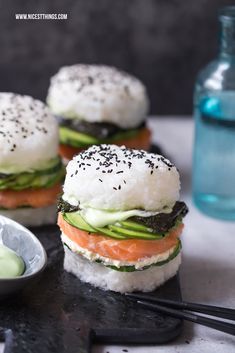 small sandwiches with cucumber, salmon and avocado are on a black tray