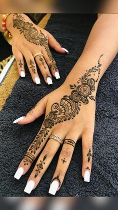 two hands with henna tattoos on them, one is white and the other is black