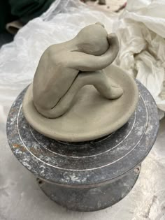 a clay sculpture sitting on top of a metal container