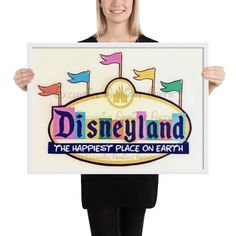 a woman holding up a sign that says disneyland the happiest place on earth