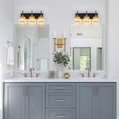 a bathroom with two sinks, mirrors and lights on the wall above them is shown