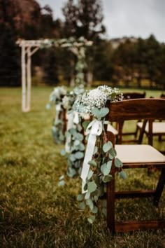 a row of wooden chairs sitting on top of a lush green field