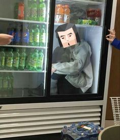 two people standing in front of a refrigerator with an image of a man sticking his head into the freezer