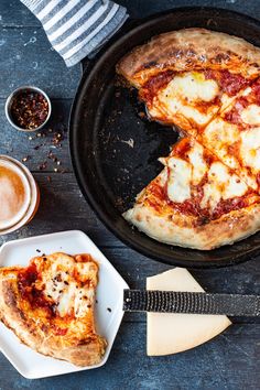 a pizza sitting on top of a pan next to a slice of cheese covered pizza