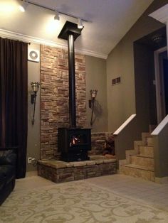 a living room with a fire place in the center and stairs leading up to it