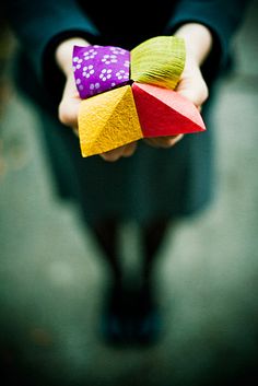 a person holding three colorful pieces of paper in their hands