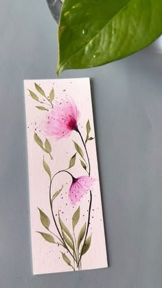 a card with pink flowers on it next to a green leaf