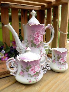 three pieces of porcelain tea set with pink flowers on them