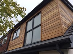 the side of a house that has wooden siding on it and black metal gutter