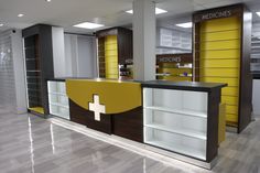 an empty pharmacy office with yellow and brown accents on the front desk, and shelves in the back