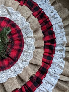 a red and black plaid hat sitting on top of a lace doily next to a pine tree