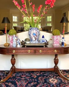 a table with vases and flowers on it in front of a large mirror,