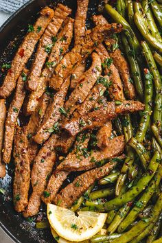 steak and asparagus in a skillet with lemon wedges on the side