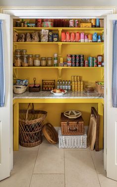 an organized pantry with yellow shelves and baskets