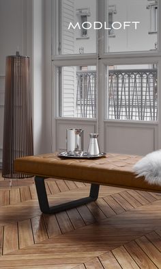 a wooden bench sitting on top of a hard wood floor next to a tall window