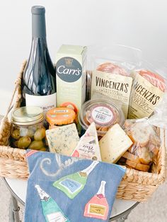 a basket filled with cheese, crackers and wine