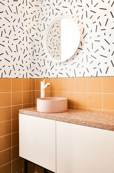 a white sink sitting under a bathroom mirror next to a wall mounted faucet