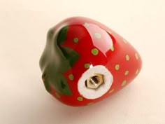 a red and green strawberry shaped object on a white surface