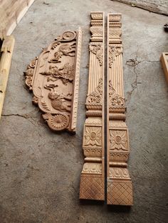 two carved wooden doors sitting on top of a cement floor next to wood planks