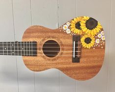 a ukulele with sunflowers and daisies painted on the fret