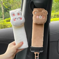 a hand holding a stuffed animal next to a car seat belt