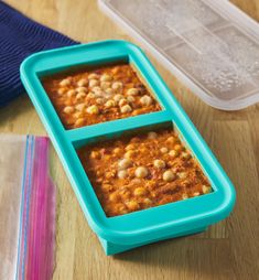 two plastic containers filled with food sitting on top of a wooden table next to a blue container