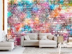 a living room with a large brick wall and colorful paint splattered on the walls