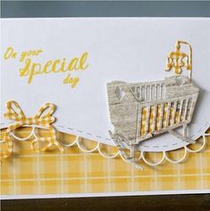 a handmade card with a baby's crib on the front and yellow ribbon around the edges