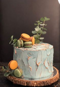 a blue cake decorated with macaroons and leaves