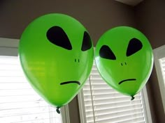 two green balloons with faces drawn on them