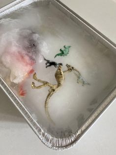 a tray filled with ice and some toy animals in it's plastic wrapper