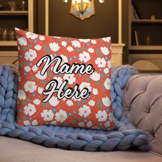 a pillow that says name here on it sitting on a couch next to a blue blanket