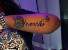 a woman with a butterfly tattoo on her arm that says breathe and butterflies around her wrist