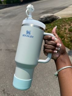 a person holding a cup in their hand on the side of the road while wearing bracelets