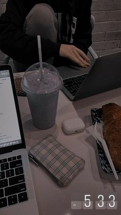 two laptops are sitting on a table with food and drink in front of them